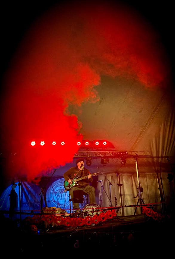 Ginger Geoffrey on stage at night surrounded by red smoke.