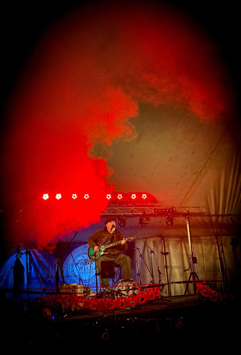 Ginger Geoffrey on stage at night surrounded by red smoke.